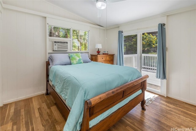 bedroom with multiple windows, wood finished floors, and access to outside