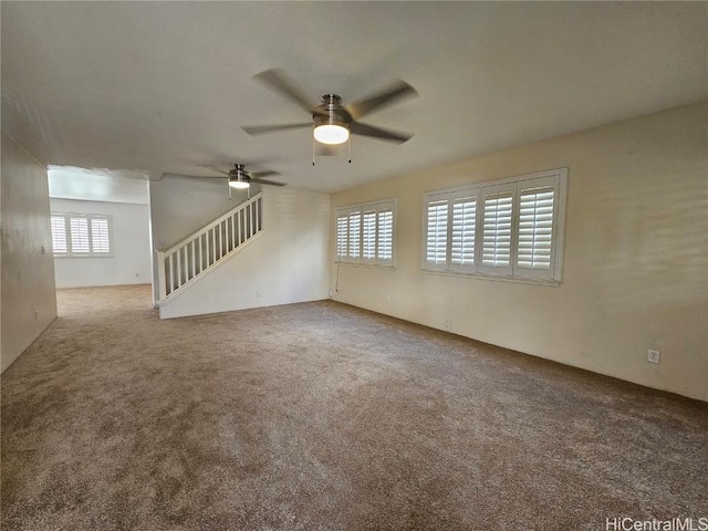 carpeted spare room with stairway and a ceiling fan