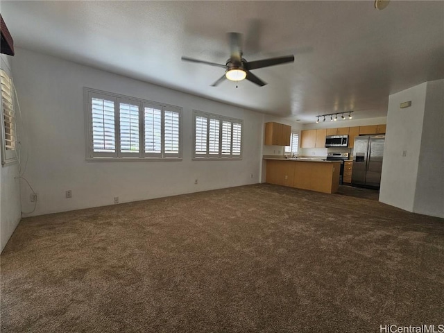 unfurnished living room featuring a sink, a ceiling fan, dark colored carpet, and track lighting