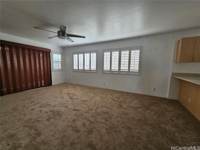 unfurnished living room featuring ceiling fan, a textured ceiling, and carpet