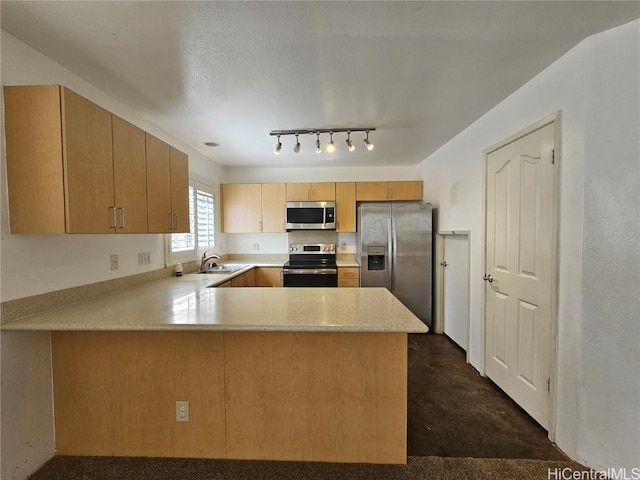 kitchen featuring stainless steel appliances, light countertops, a sink, concrete flooring, and a peninsula