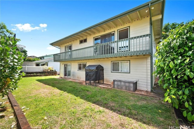 rear view of property featuring a balcony and a lawn