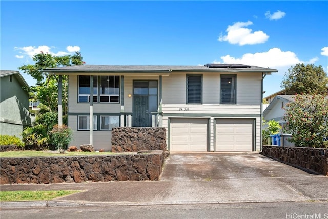 split foyer home featuring concrete driveway, roof mounted solar panels, and an attached garage