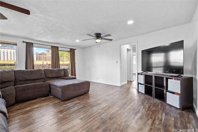 living room with a textured ceiling, wood finished floors, a ceiling fan, and recessed lighting