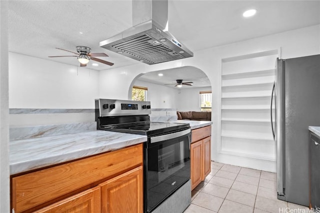 kitchen with arched walkways, light tile patterned floors, recessed lighting, appliances with stainless steel finishes, and wall chimney exhaust hood