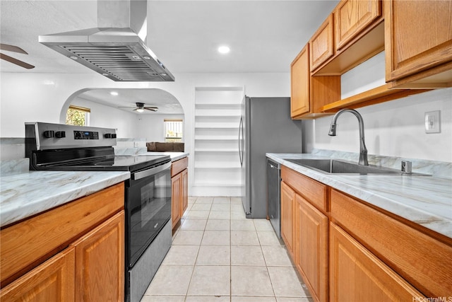 kitchen with a sink, wall chimney exhaust hood, ceiling fan, and stainless steel appliances