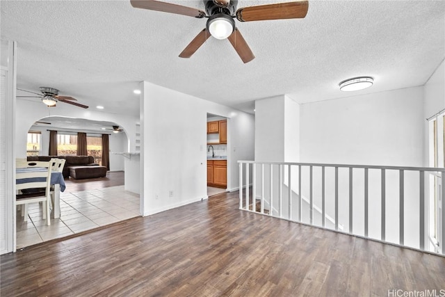 spare room featuring a textured ceiling, arched walkways, a sink, and wood finished floors