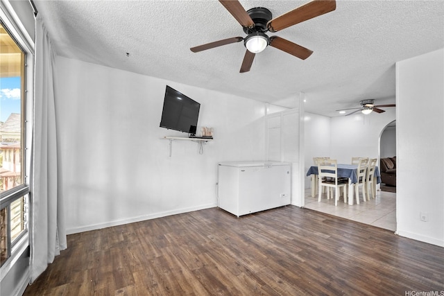 unfurnished living room with a textured ceiling, ceiling fan, and wood finished floors