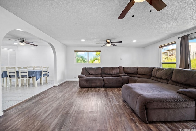 living room with arched walkways, ceiling fan, and wood finished floors