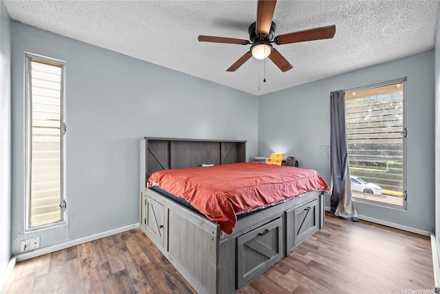 bedroom with dark wood-type flooring, a textured ceiling, baseboards, and ceiling fan