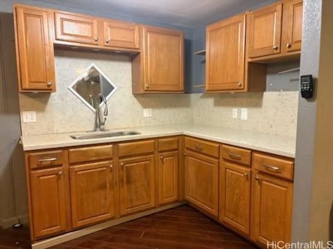 kitchen featuring light countertops, dark wood-style flooring, decorative backsplash, and a sink