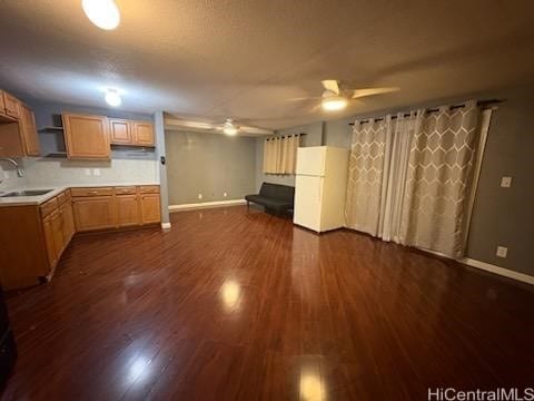 kitchen featuring a ceiling fan, dark wood-style flooring, baseboards, light countertops, and a sink