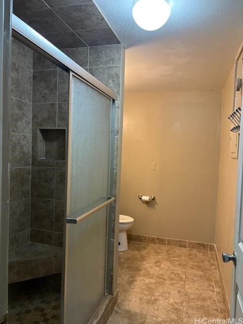 bathroom featuring baseboards, a stall shower, and toilet