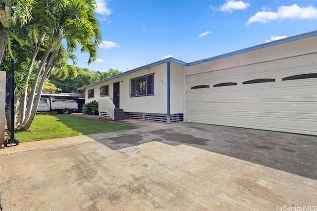 single story home with entry steps, an attached garage, concrete driveway, and a front lawn