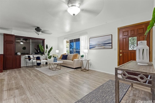 living room featuring baseboards, light wood finished floors, and ceiling fan