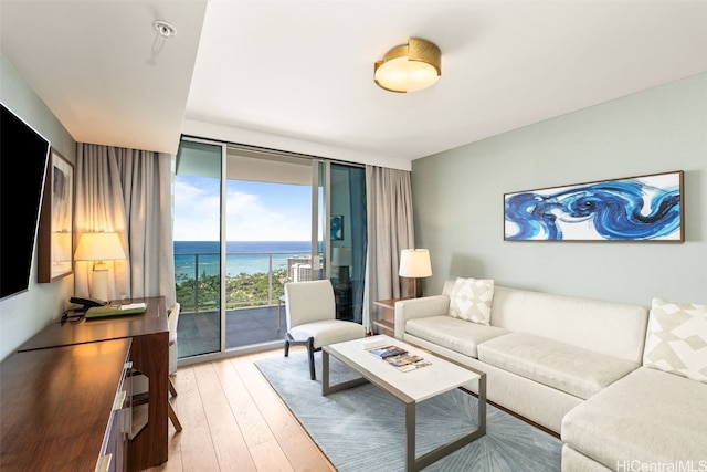 living area featuring a wall of windows, light wood-style floors, and a water view