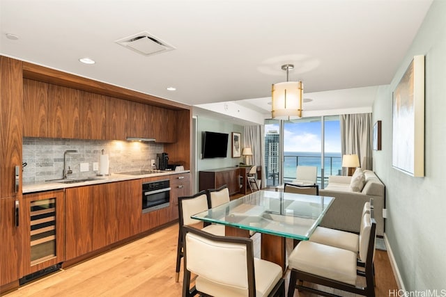 kitchen with brown cabinetry, visible vents, a sink, light countertops, and wall oven