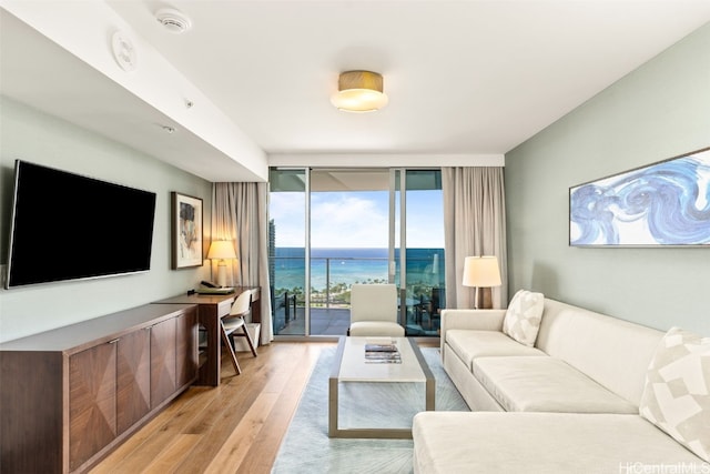 living room featuring light wood-type flooring, a water view, and floor to ceiling windows