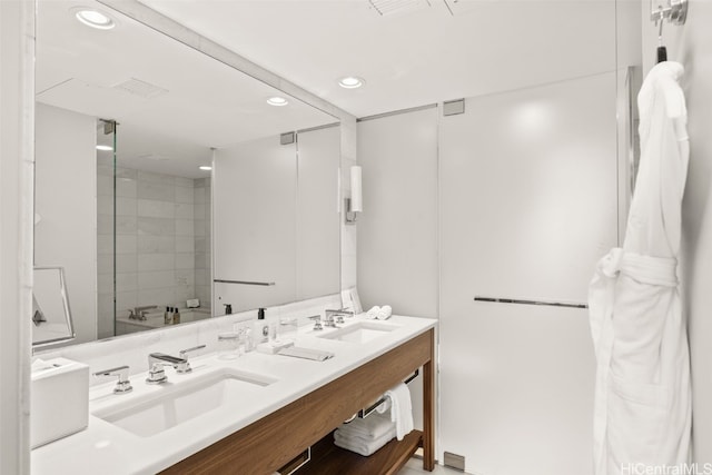 bathroom with double vanity, recessed lighting, walk in shower, and a sink