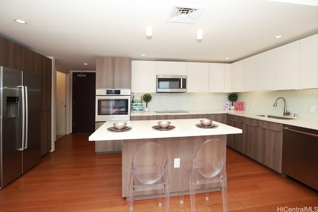 kitchen with stainless steel appliances, modern cabinets, light countertops, and a sink