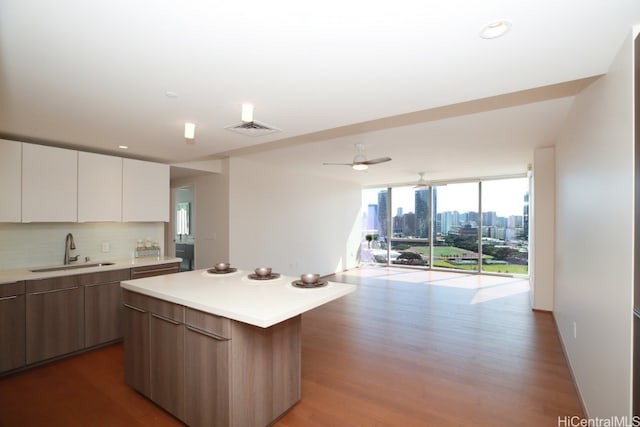 kitchen with open floor plan, light countertops, decorative backsplash, modern cabinets, and a sink