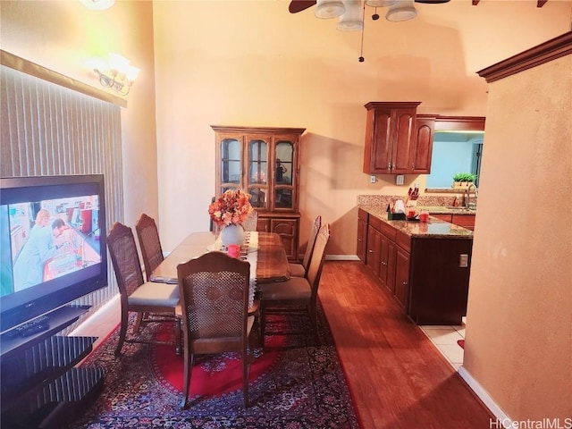 dining space featuring dark wood-style floors, a high ceiling, ceiling fan, and baseboards