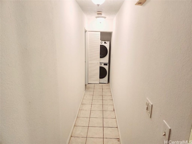 hallway with stacked washer and dryer and light tile patterned flooring