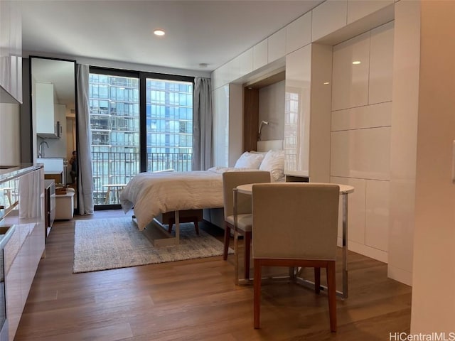 bedroom with expansive windows and wood finished floors