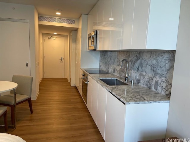 kitchen featuring visible vents, appliances with stainless steel finishes, light wood-style floors, white cabinetry, and a sink