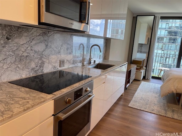 kitchen with modern cabinets, a sink, dark wood finished floors, white cabinetry, and stainless steel appliances