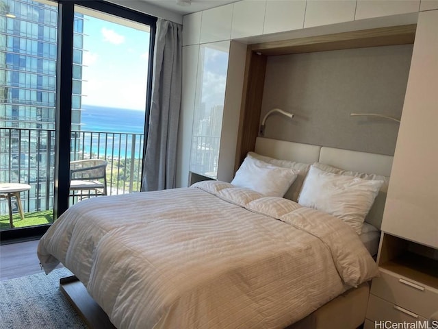 bedroom with access to outside, wood finished floors, and a water view