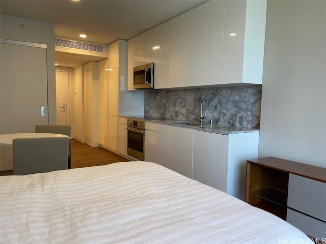 bedroom with visible vents, recessed lighting, wood finished floors, and a sink