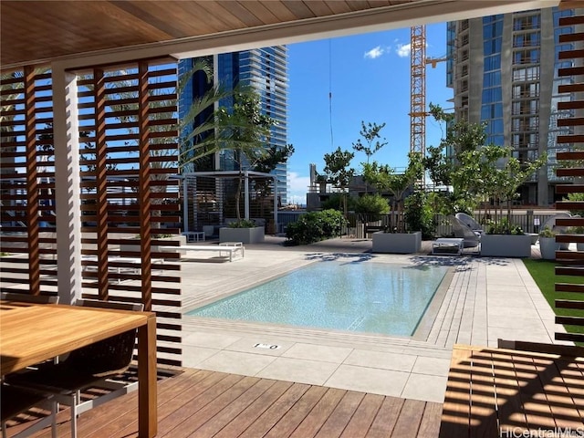 view of pool featuring a city view, a patio, and fence