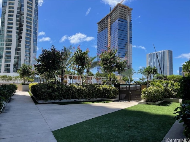 view of property's community featuring a lawn, a city view, and a gate