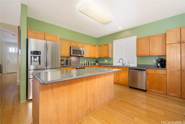 kitchen featuring light wood-style flooring, a kitchen island, stainless steel appliances, light brown cabinets, and a sink