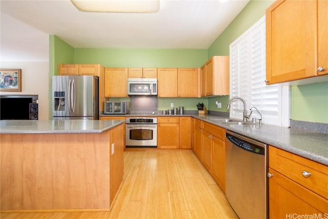 kitchen with light wood-type flooring, light brown cabinets, stainless steel appliances, and a sink