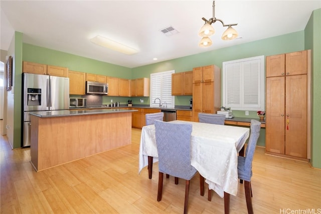 kitchen featuring a notable chandelier, visible vents, appliances with stainless steel finishes, a center island, and light wood finished floors