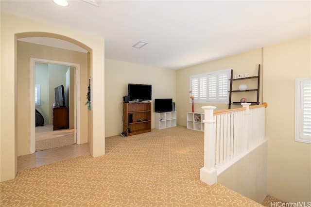 interior space with carpet floors, arched walkways, and an upstairs landing