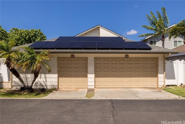 garage featuring solar panels, concrete driveway, and fence