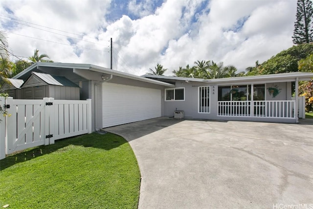 view of front of home featuring an attached garage, driveway, a front lawn, and fence