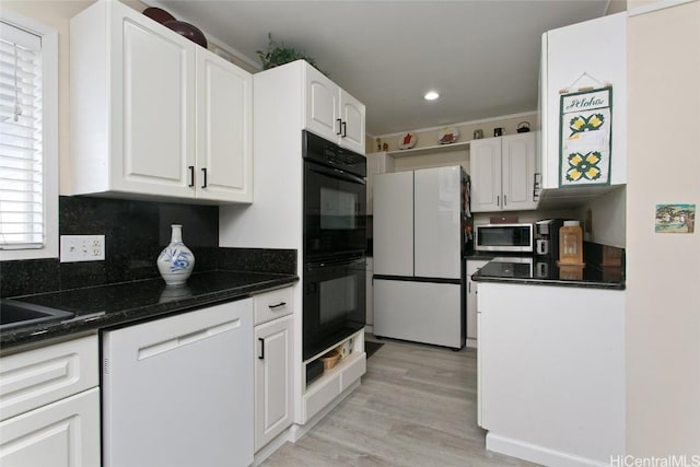 kitchen featuring dark stone countertops, backsplash, white cabinetry, white appliances, and light wood-style floors