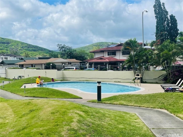 view of pool featuring a fenced in pool, a mountain view, a lawn, and fence