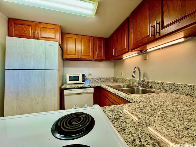 kitchen featuring brown cabinets, white appliances, light countertops, and a sink