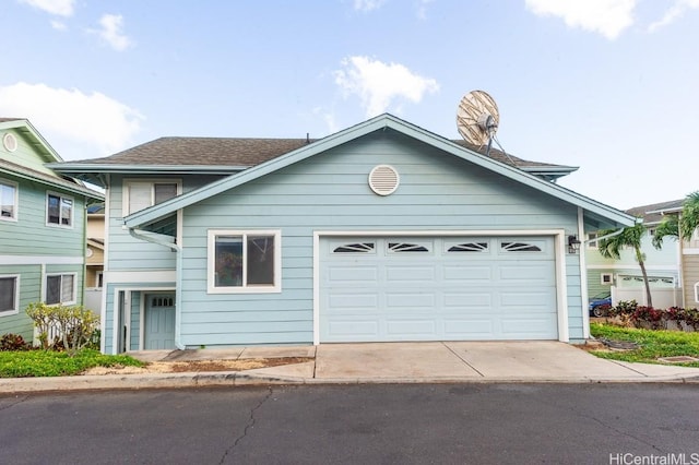 view of front of property featuring a garage, driveway, and a shingled roof