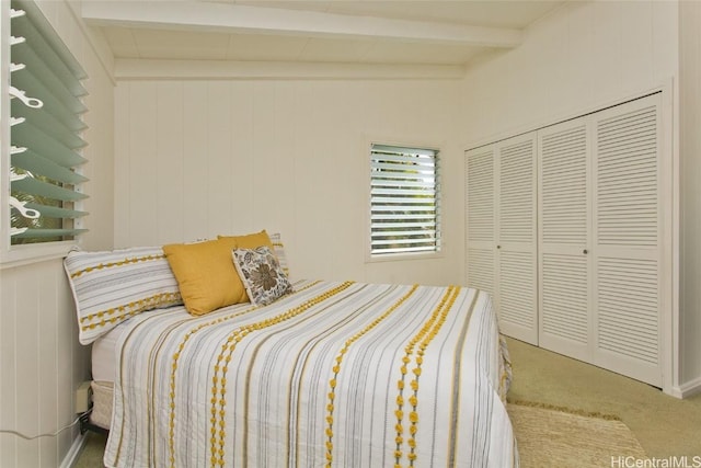 bedroom with beam ceiling, a closet, and carpet floors