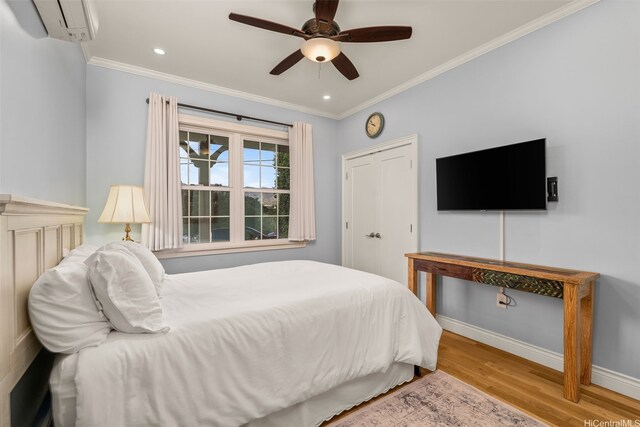 bedroom with crown molding, ceiling fan, a wall mounted air conditioner, baseboards, and wood finished floors