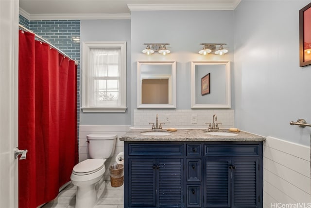 bathroom featuring ornamental molding, toilet, wainscoting, and a sink