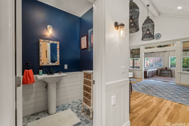 bathroom featuring lofted ceiling with beams, wood finished floors, a wainscoted wall, and ornamental molding