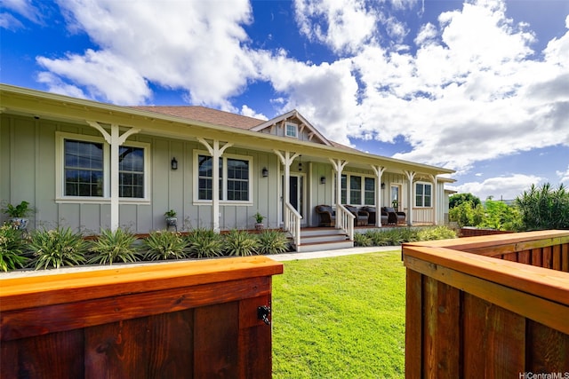 view of front of house featuring roof with shingles, covered porch, board and batten siding, and a front yard