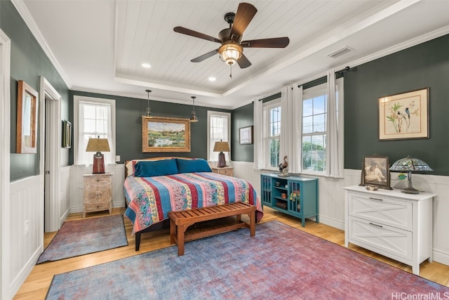 bedroom with visible vents, multiple windows, a raised ceiling, and a wainscoted wall